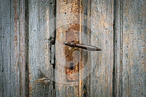 Antique rusty doorknob on an ancient wooden door of an old farm barn