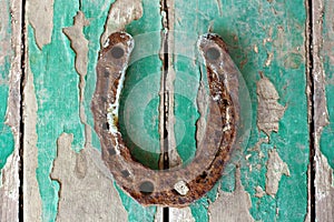 Antique rusty horseshoe on weathered green wooden surface