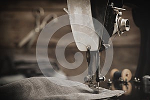 Antique sewing machine with linen cloth. In the background is a hanging tailoring scissors. Retro tailor workshop