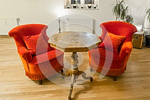 Antique side table with intarsia and red chair