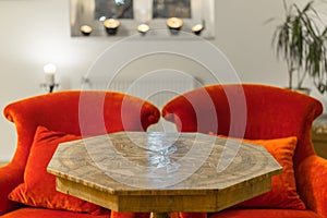 Antique side table with intarsia and red chair