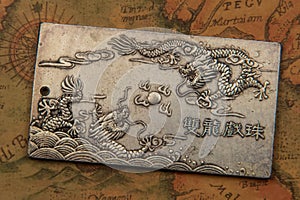 Antique silver plate with fighting dragons On Ancient oriental-style World Map
