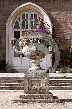 antique Stone urn garden planter withflowers in English garden