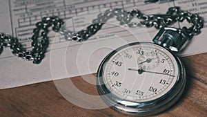Antique Stopwatch Lies on Wooden Desk with Old Documents and Counts Seconds