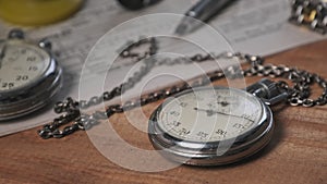 Antique Stopwatch Lies on Wooden Desk with Old Documents and Counts Seconds