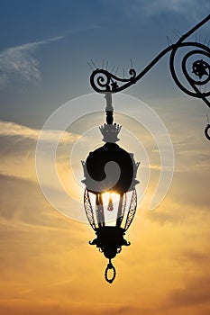 Antique street lamp lantern over sunset sky