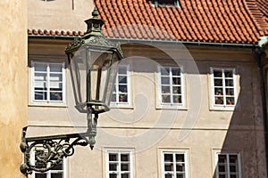 Antique street lantern on wall in the old town of Prague, Czech Republic. Old street light against windows and roof tile