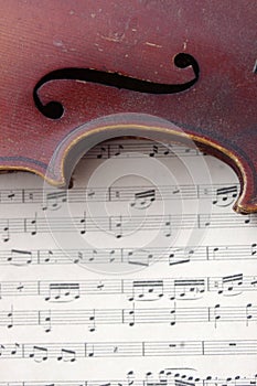 Antique string violin on white sheet music close up