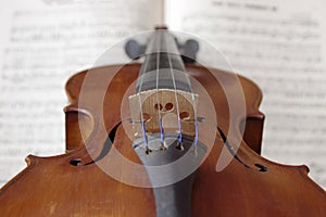 Antique string violin on white sheet music close up