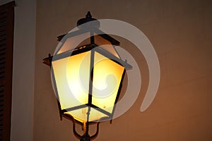 Antique style lamppost lantern attached to wall of building. Light on