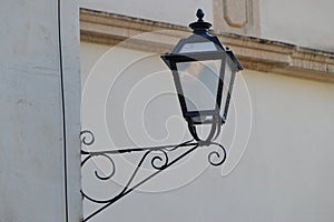 Antique style lamppost lantern attached to wall of building. Light off