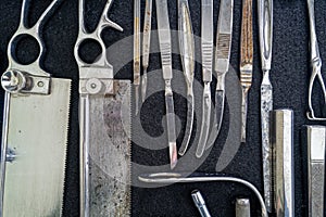 Antique surgical saws are laid out on black felt