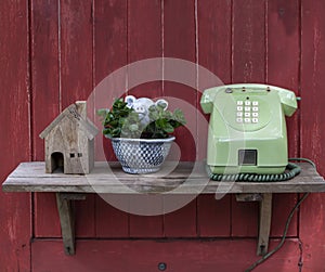 An antique telephone is placed on a shelf behind a red wooden plank