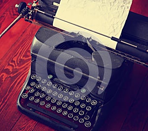 An antique typewriter on a wooden table toned with a retro vint
