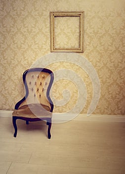 Antique upholstered chair in a wallpapered room