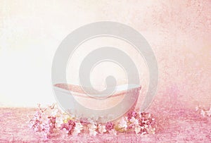 An antique Victorian bathtub with pink flowers and a pink textured background.