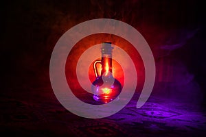 Antique and vintage glass bottles on dark foggy background with light. Poison or magic liquid concept.