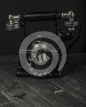 An antique vintage manual telephone is locked by a padlock marked code