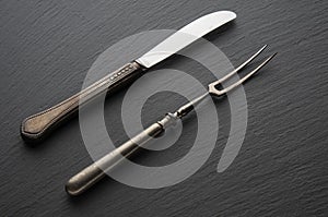 Antique, vintage metal knife and fork on a black background