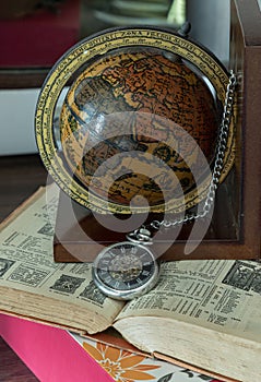Antique Vintage pocket watch and Wooden Globe placed on and old book
