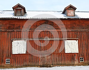 Antique vintage red gable barn with sliding doors and dormer roof windows