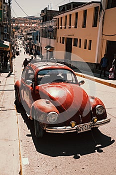 Antique Volkswagen Beetle is parked on the side of a quiet road.