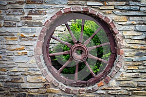 Antique and weathered wood cart wagon wheel in old stone farm bu