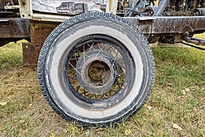 An antique whitewall tire with spokes resting in the grass