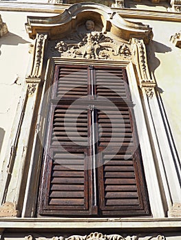 Antique window with shutters. An ornate stucco window in a stone house. Wooden frame, Venetian - brown shutters or