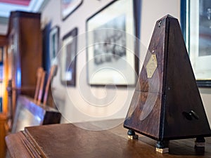 An antique wooden brown metronome on a wall of photographs