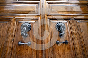 Antique wooden door with hand-shaped knockers