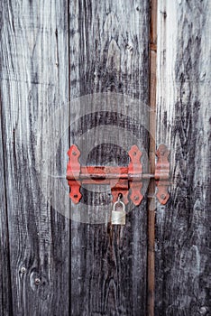 Antique wooden gray door with a metal red lock