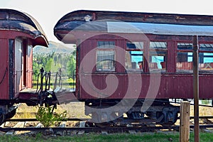 Antique wooden passenger rail cars parked on a train track