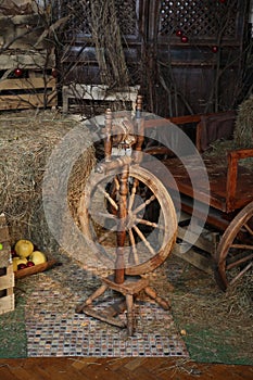 Antique wooden spinning wheel with a spindle on a hay background