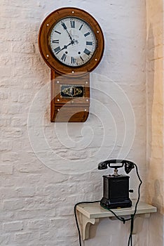 Antique wooden telephone and clock on white wall
