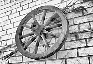 Antique wooden wagon wheel hanging on a brick wall.