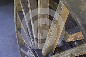 Antique wooden wagon wheel with metal rim standing upright in the garage