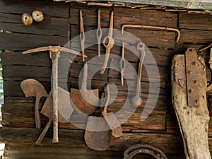 Antique yard tools hang on the outer wall of a shed photo