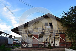Antique yellow wooden barn with red wooden doors that closed with crossing wood.