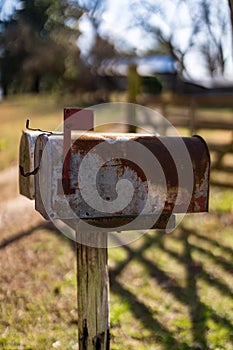 Antiqued metal mail box mounted on a wooden post, featuring a traditional red top