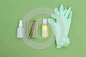 Antiseptic, rubber gloves and aloe vera leaf on green background. Flat lay. Undertone photo