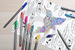 Antistress coloring page and felt tip pens on light wooden table, flat lay