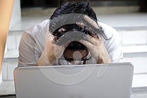 Anxiety confused young Asian business man with laptop covering face with his hands