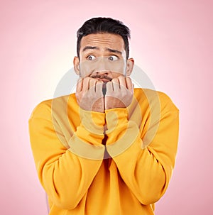 Anxiety, thinking and asian man biting nails in studio with terror, fear and scared for drama on pink background. Stress