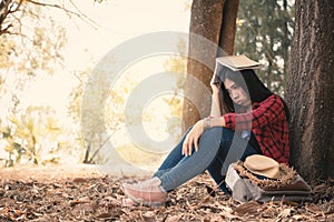 Anxiety woman about her studying sitting lonely under the big tree on park