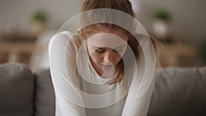 Anxious addicted young woman sitting alone on couch at home