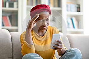 Anxious african amerian woman reading message on phone