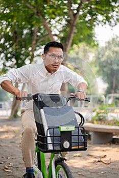 An anxious Asian businessman is in a hurry to get to work in the morning, riding a bike