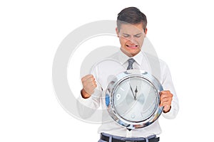 Anxious businessman holding and looking at clock