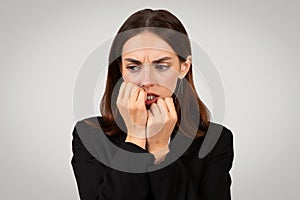 Anxious businesswoman biting her nails with a look of deep concern on her face